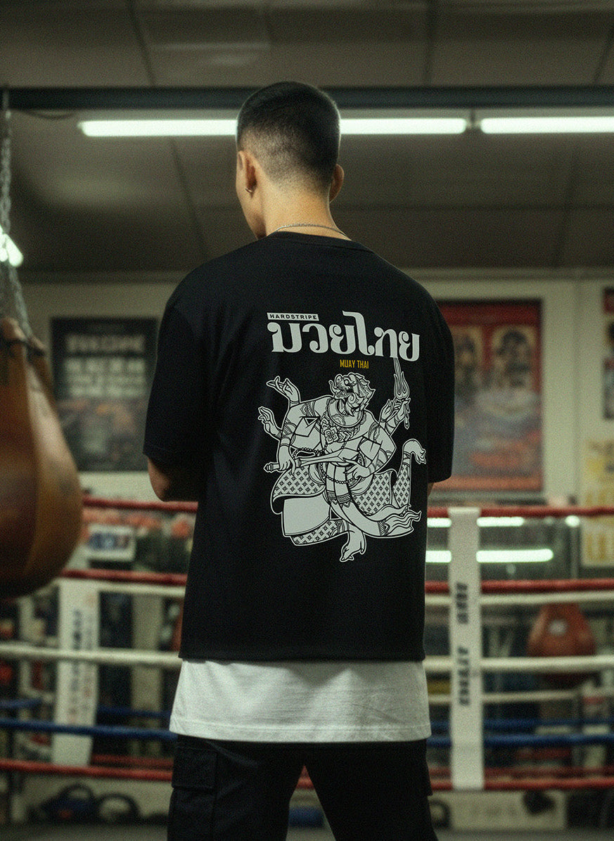 Person wearing a black t-shirt with white graphics in a boxing ring.